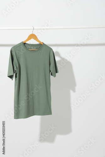 Green t shirt on hanger hanging from clothes rail with copy space on white background