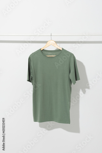 Green t shirt on hanger hanging from clothes rail with copy space on white background