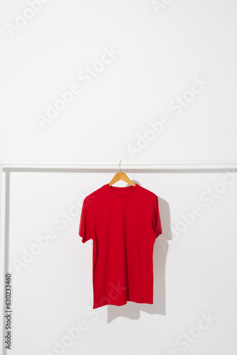 Red t shirt on hanger hanging from clothes rail with copy space on white background