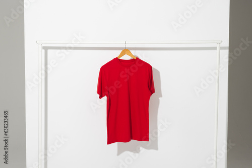 Red t shirt on hanger hanging from clothes rail with copy space on white background