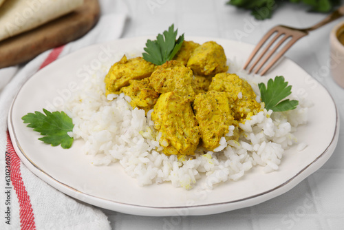 Delicious rice and chicken with curry sauce on white tiled table, closeup