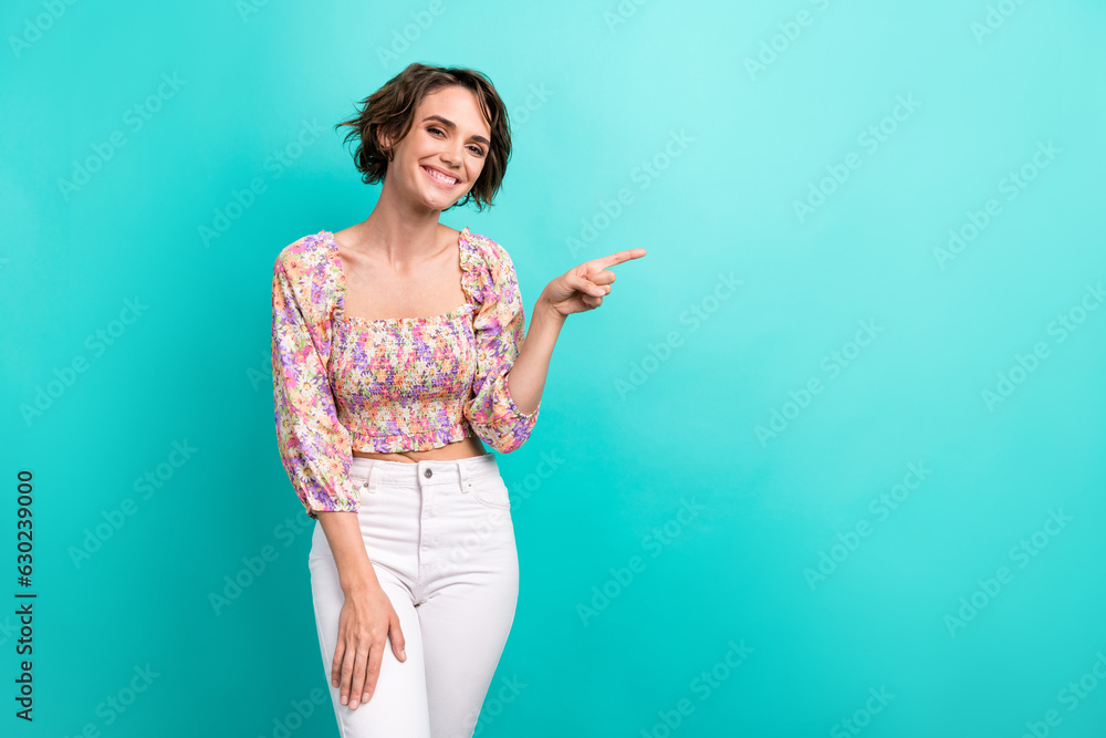 Photo of toothy beaming woman with short hairstyle wear colorful top indicating empty space sale isolated on turquoise color background Photo of toothy beaming woman with short hairstyle wear colorful top indicating empty space sale isolated on turquoise color background