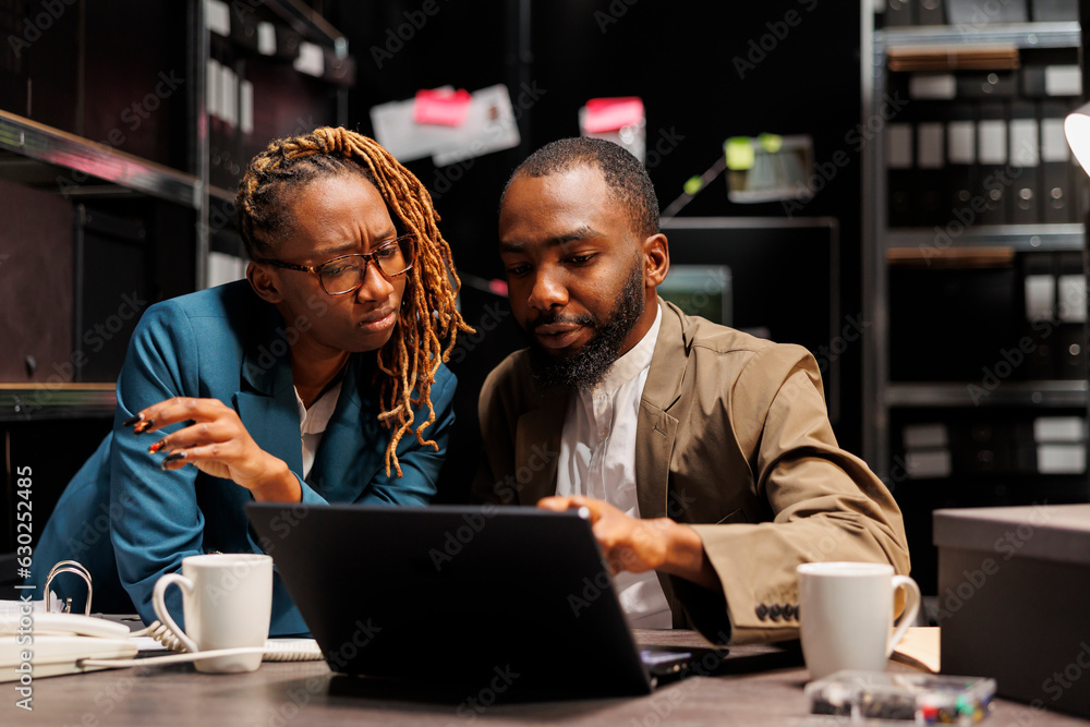 African american criminologists colleagues conducting investigation research in detective office. Man and woman law eneforcement professionals studying crime case on laptop together