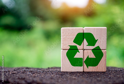 Concepts of waste reduction, pollution, reuse, efficient use of resources. Environmental protection sign by recycling on circular wooden blocks on nature background.
