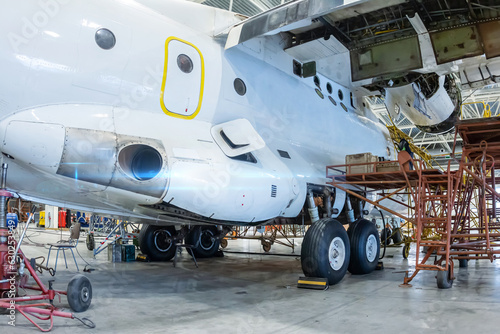 White transport airplane in the hangar. Aircraft under maintenance. Checking mechanical systems for flight operations