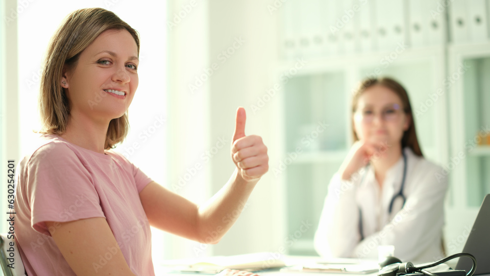 Smiling woman patient showing thumb up at doctor appointment. Quality professional medical care Smiling woman patient showing thumb up at doctor appointment. Quality professional medical care
