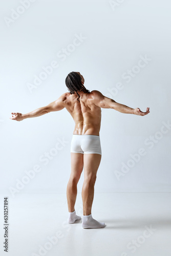 Rear view image of man posing shirtless in underwear against grey studio background. Relief back, muscular, healthy body. Concept of men's beauty, body care, sport, wellness, healthy lifestyle, ad