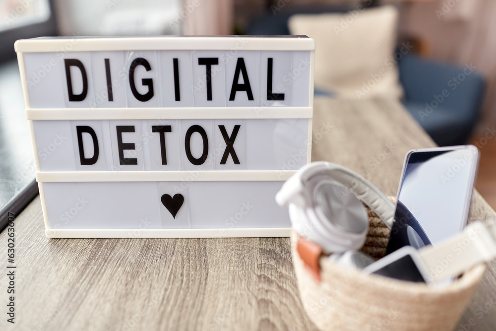 technology concept - digital detox words on light box and different gadgets on blue background technology concept - digital detox words on light box and different gadgets on blue background