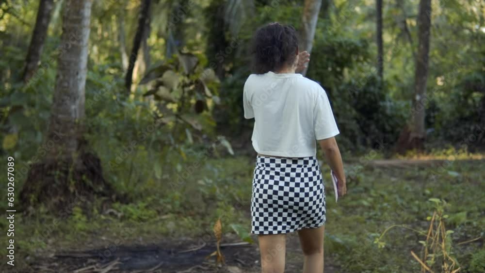 Cinematic slow motion shot of a fashion model walking through the forest in Goa, India in a chess patterned skirt and a white shirt Cinematic slow motion shot of a fashion model walking through the forest in Goa, India in a chess patterned skirt and a white shirt