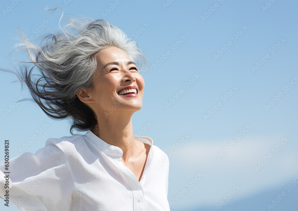 風が吹く空の下で笑顔の日本人シニア女性