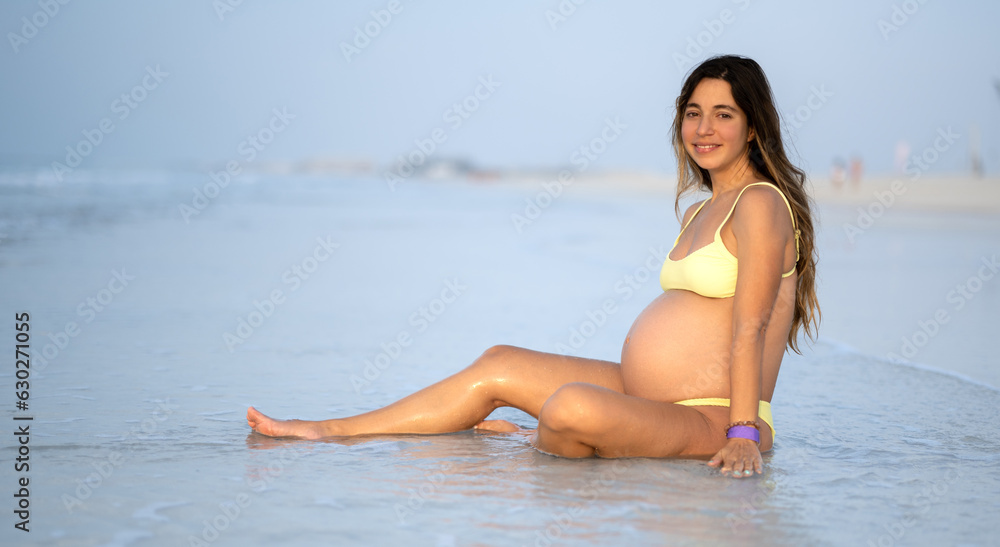 Young 9 months pregnant woman relaxing on sandy beach in summer day. Young 9 months pregnant woman relaxing on sandy beach in summer day.