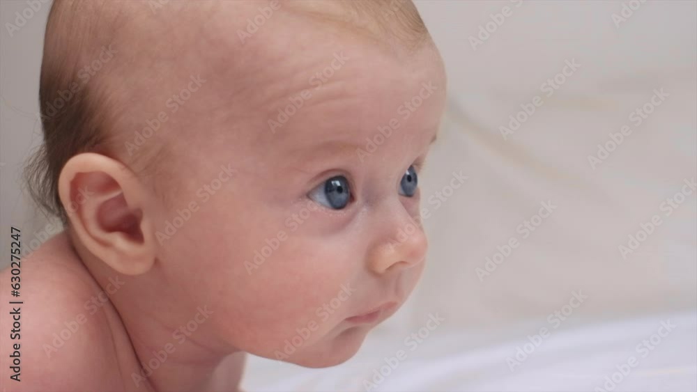 Close-up portrait of peaceful cute Caucasian newborn infant boy. Curious smart adorable kid toddler on comfortable white bed at home. Childcare, bedtime, daily routine concept. Selective focus Close-up portrait of peaceful cute Caucasian newborn infant boy. Curious smart adorable kid toddler on comfortable white bed at home. Childcare, bedtime, daily routine concept. Selective focus