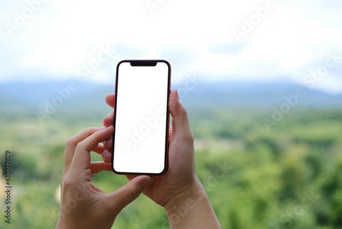 Unrecognizable man hands holding smartphone with blurred​ mountain scape background