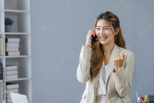 Happy smiling success and excited Asian woman with smartphone in office, Excited black woman or winner celebrate winning concept. 