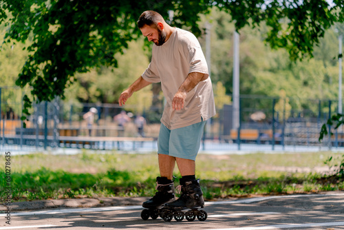 Young guy with a beard learns to rollerblade in a city park concept of wanting to learn new things and body positivity 