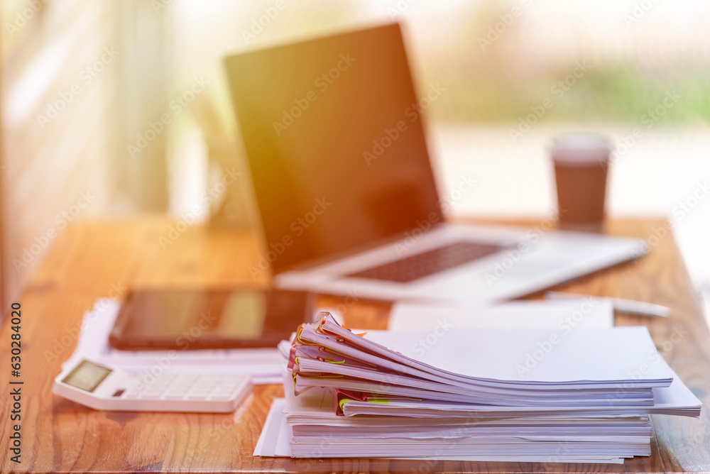 Paper documents are stacked on wooden desks at the workplace. Paper documents are stacked on wooden desks at the workplace.