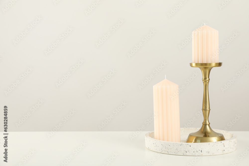 Candles in holder and ceramic plate on light background, space for text Candles in holder and ceramic plate on light background, space for text