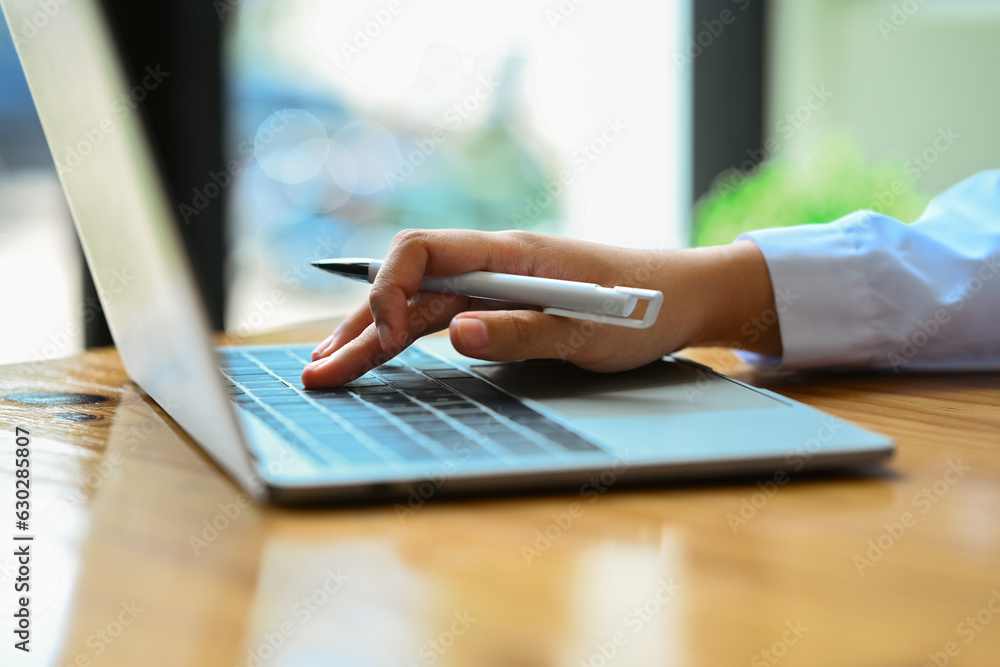 Side view of female worker hand typing on laptop, searching information, browsing internet, working online Side view of female worker hand typing on laptop, searching information, browsing internet, working online