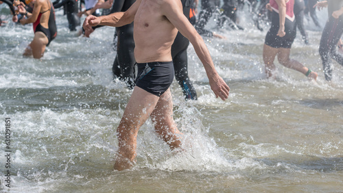 Cutout of an old man in swimming trunks running into a lake at a triathlon competition
