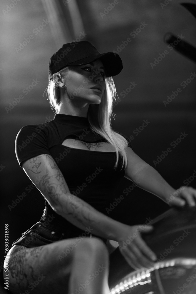 Beautiful blonde girl posing while sitting on motorcycle in the parking Beautiful blonde girl posing while sitting on motorcycle in the parking