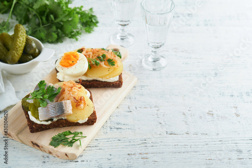 Open sandwich or smorrebrod with rye bread, herring, eggs, caramelized onions, parsley and cottage cheese on old wooden rustic table backgrounds. Danish or Scandinavian traditional food snack lunch. photo