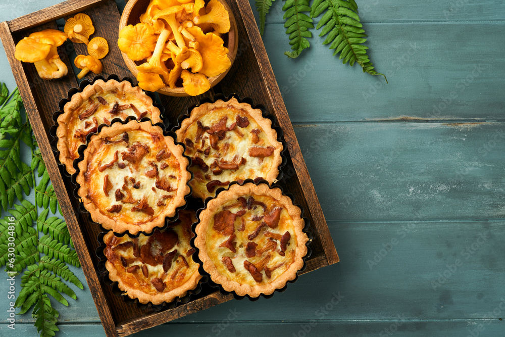Savory hands pie with chanterelle mushrooms, cream and cheese on cutting board on rustic old wooden table background. Homemade tarts with seasonal chanterelle mushrooms. Rustic style. Top view. Savory hands pie with chanterelle mushrooms, cream and cheese on cutting board on rustic old wooden table background. Homemade tarts with seasonal chanterelle mushrooms. Rustic style. Top view.