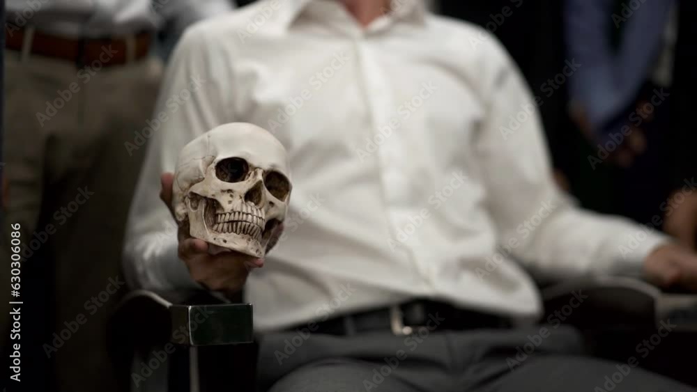 Man in suit is holding a skull in his hands. Concept of mafia and banditry.