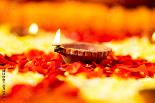 Close up shot of diya or oil lamp placed on flowers during diwali festival celebration - concept of treaditional indian culutre, and occasion photo