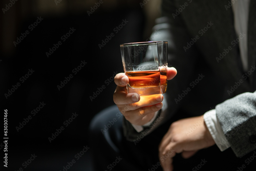 Businessman sitting and holding glass of whiskey..
