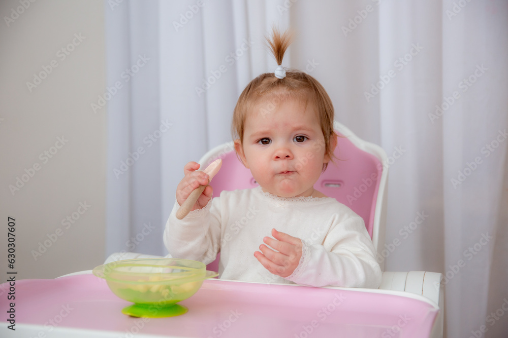 cute baby eats in a high chair made of silicone baby dishes. Baby food, space for text cute baby eats in a high chair made of silicone baby dishes. Baby food, space for text