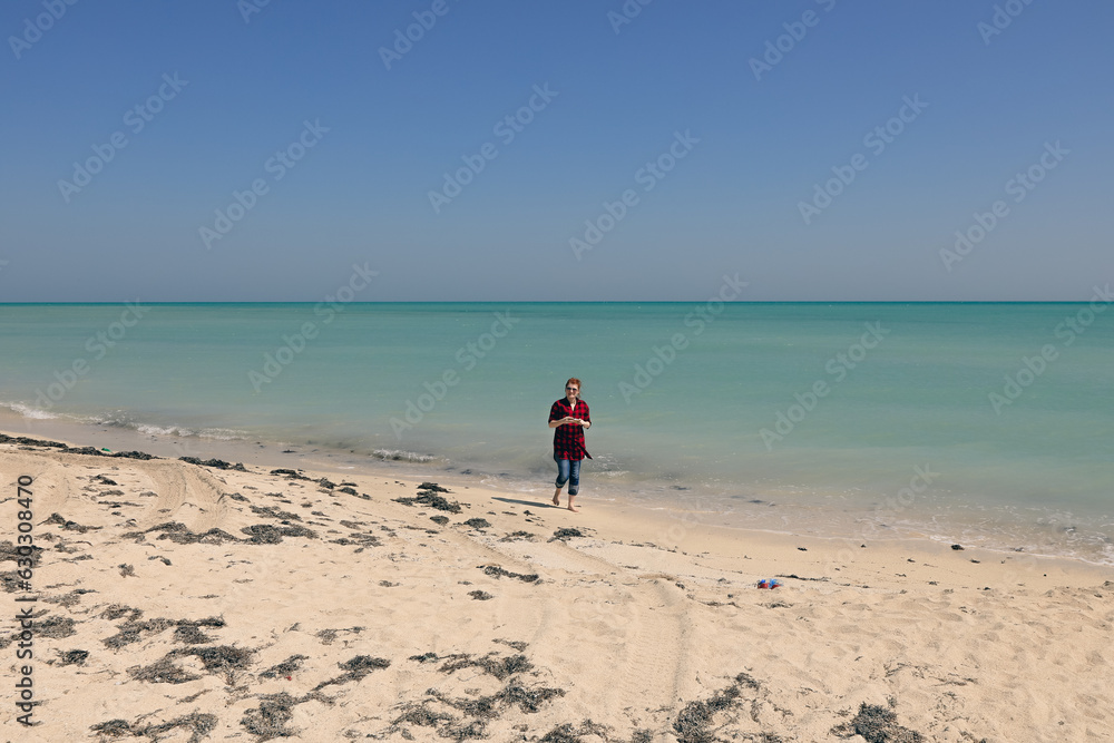 Tourists enjoying of the warm Golden Sand and Blue water on the coast of Persian bay near Doha, Qatar