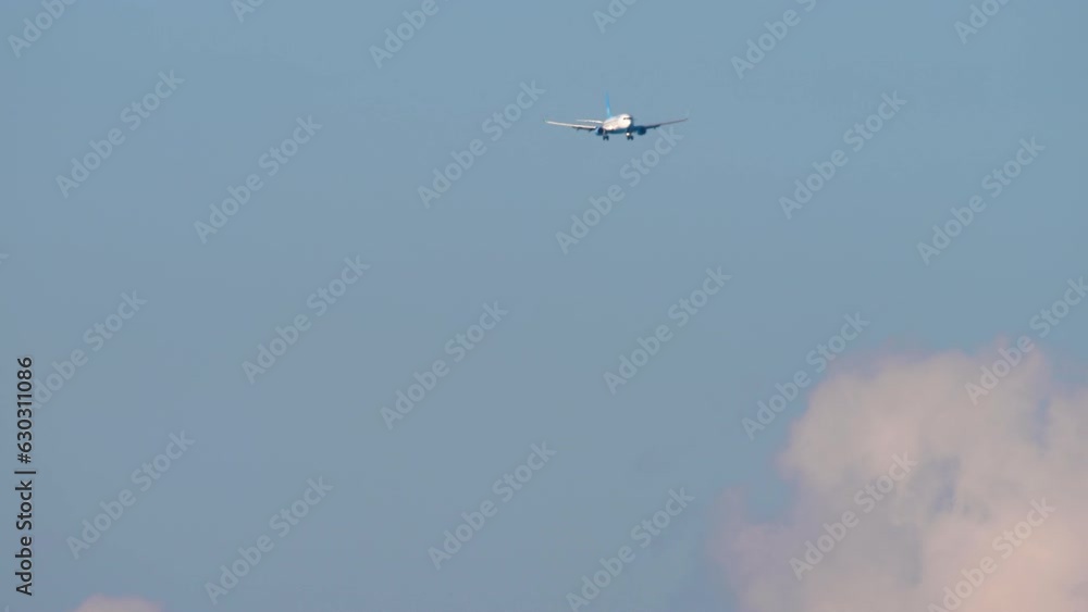 Jet passenger plane approaching to land in sunny cloudy sky. Unrecognizable airliner high in the sky Jet passenger plane approaching to land in sunny cloudy sky. Unrecognizable airliner high in the sky