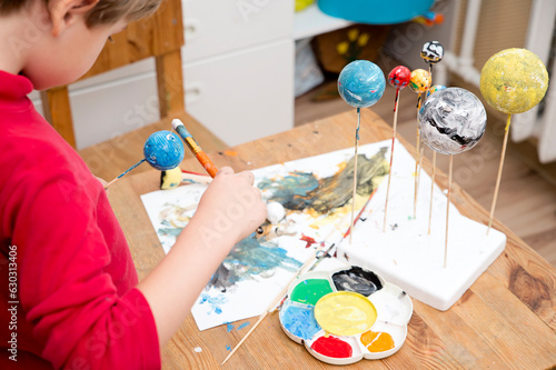 Obraz na plátně Boy painting styrofoam balls when making model of Solar System for school