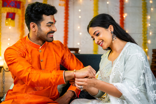 Murais de parede Indian sister tying rakhi to brother during raksha Bandhan fetival at home - con
