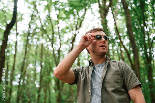 In sunglasses. Tourist in summer forest. Conception of exploration and leisure