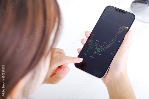Fotografie 投資した資産をスマホで確認する女性