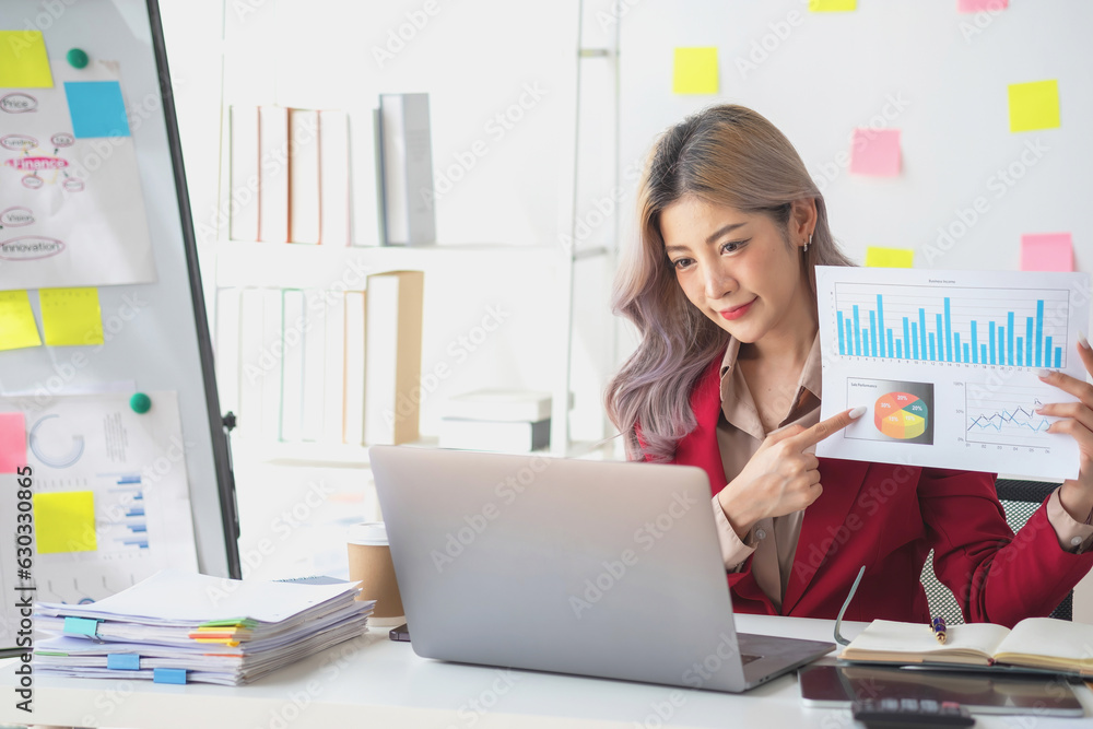 Asian businesswoman presenting a profitable company marketing plan with confidence at the office and future investment plans of the company with charts and graphs on the board. Asian businesswoman presenting a profitable company marketing plan with confidence at the office and future investment plans of the company with charts and graphs on the board.