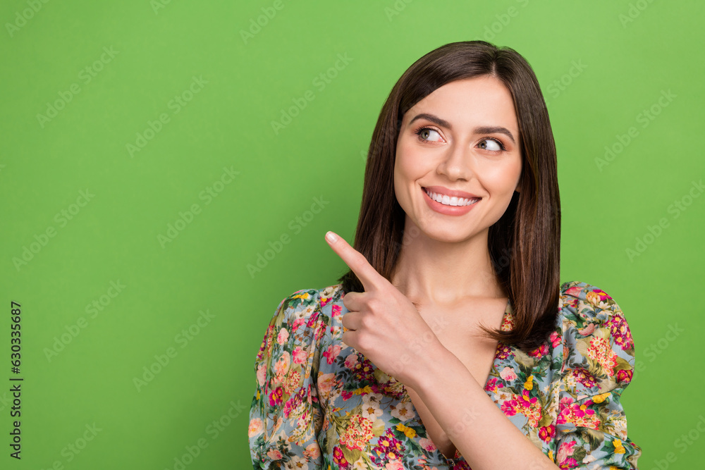 Photo portrait of charming lady directing finger empty space poster wear vintage floral blouse isolated green color background Photo portrait of charming lady directing finger empty space poster wear vintage floral blouse isolated green color background