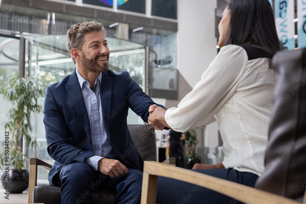 Businessman shaking hands with businesswoman in a corporate office Businessman shaking hands with businesswoman in a corporate office