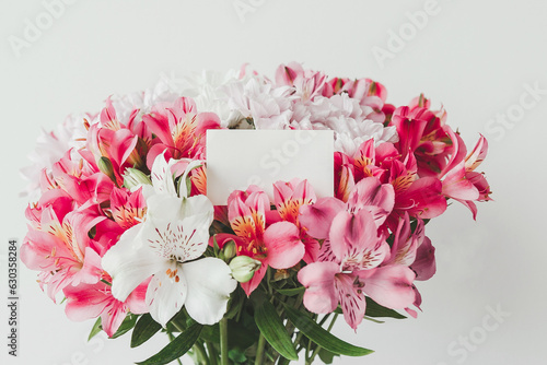 Bright beautiful bouquet of alstroemerias and chrysanthemums on a white background with an empty gift card for your text photo