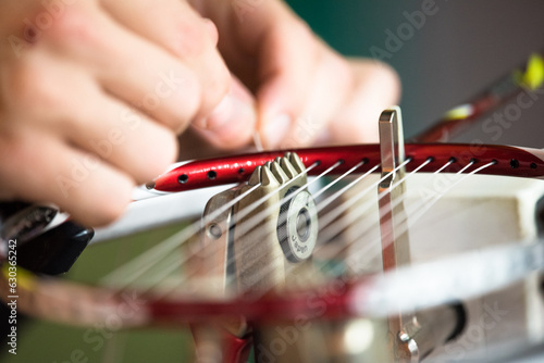 Closeup of a Japanese badminton weaving machine for repairing of broken badminton strings - a male hand weaves strings in a badminton racket head. photo