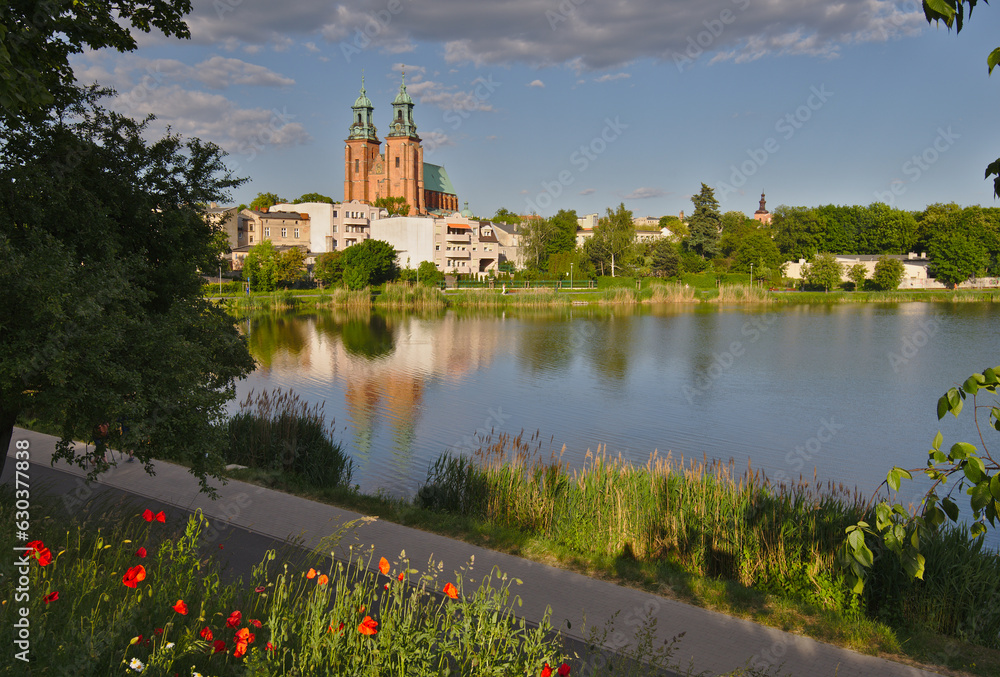 Gniezno town in summer, Poland. The architecture of the city with the dominant Primate's Basilica reflects in the waters of Lake Jelonek. Gniezno town in summer, Poland. The architecture of the city with the dominant Primate's Basilica reflects in the waters of Lake Jelonek.