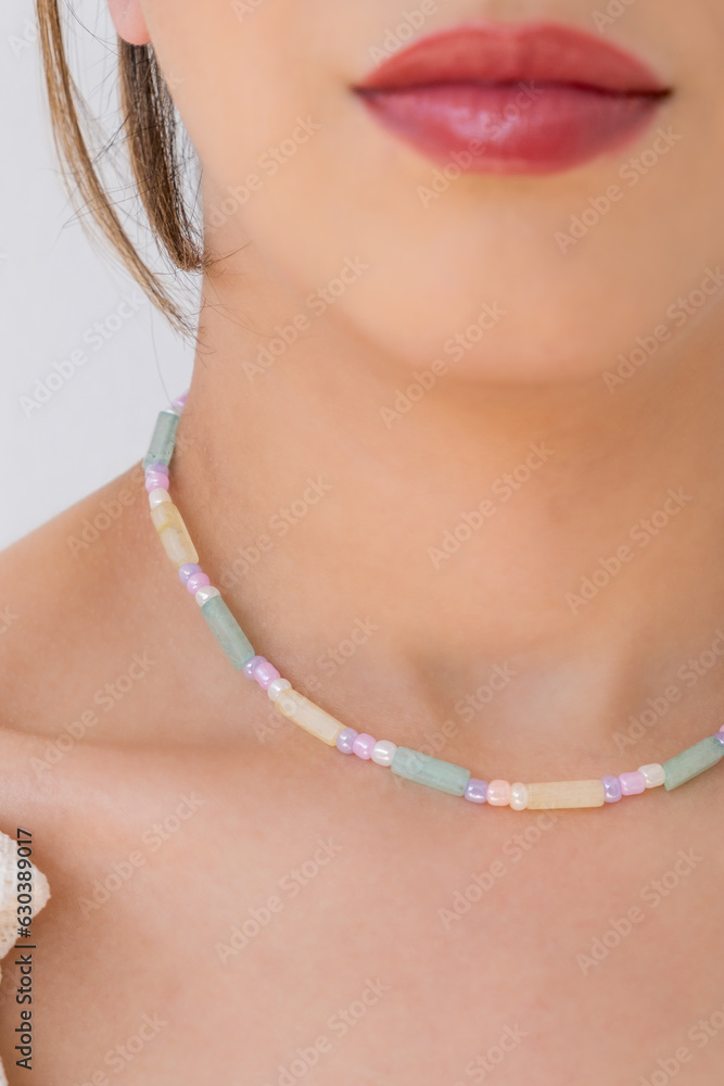 Young woman wearing a jade necklace in pastel colors.