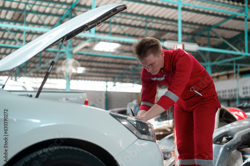Young caucasian repairman analyzing and fixing broken car in car repair mechanic shop © tonefotografia