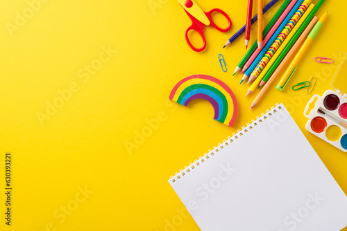 Grab attention of parents and educators with eye-catching top view image, featuring album and variety of colorful school supplies. Enhance your educational campaigns with yellow isolated background