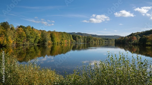 Tranquil Henne Lake surrounded by vibrant foliage in Sauerland, Germany