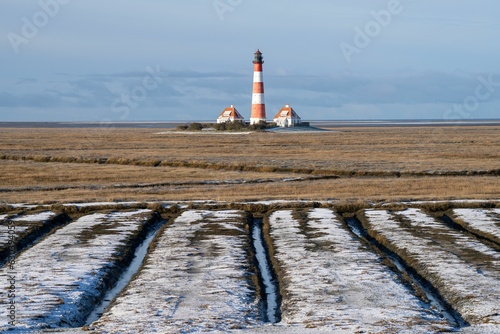 Lighthouse in a rural winter landscape seen through fields in Westerhever, North Sea, Germany photo