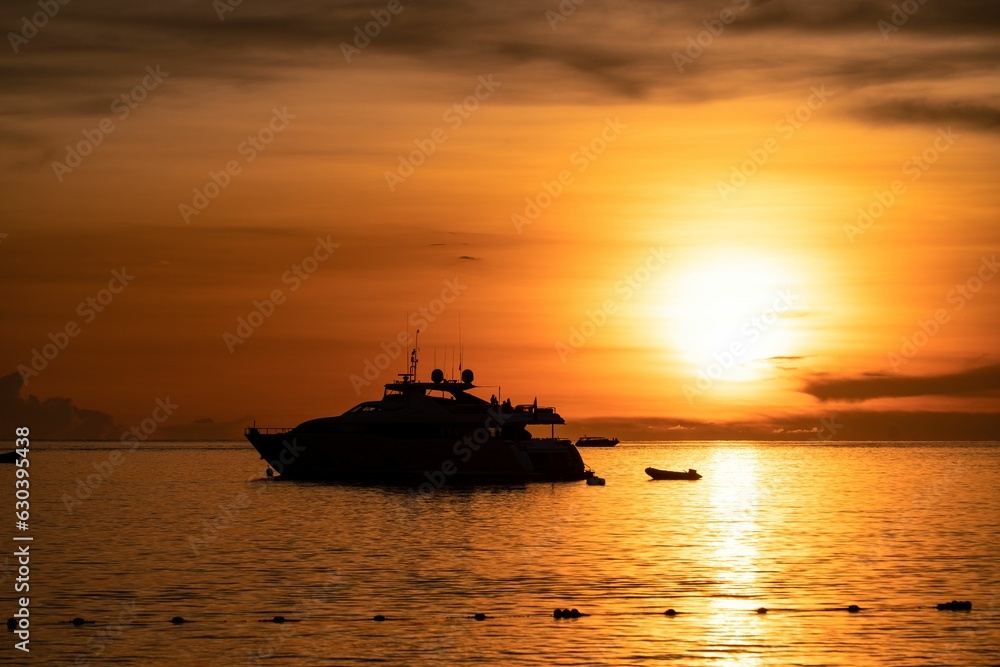 Yacht on the sea silhouetted against a vibrant orange sunset