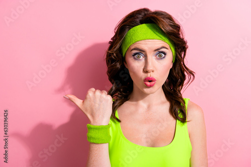Portrait of impressed crazy fitness girl pouted lips indicate finger empty space ad isolated on pink color background