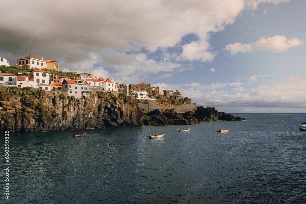 Stunning Madeira Island featuring residential buildings on the rocky shore and boats on water